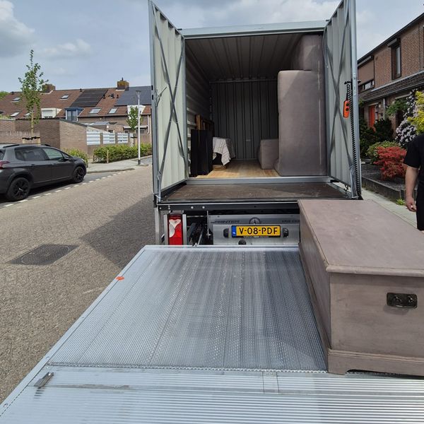 Meubel inladen via laadklep bakwagen in woonwijk – mobiele opslagcontainer 16 m³ Meubel wordt via laadklep ingeladen in bakwagen met mobiele opslagcontainer in woonwijk – Eenvoudig Mobiel Opslaan