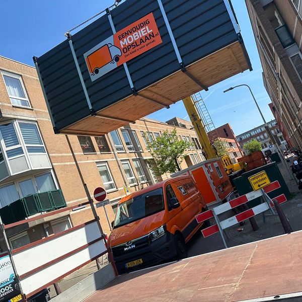 Opslagcontainer plaatsing met kraan in smalle stadsstraat – ook op moeilijk bereikbare locaties Opslagcontainer aan kraan boven stadsstraat – container voor de deur plaatsen bij Eenvoudig Mobiel Opslaan