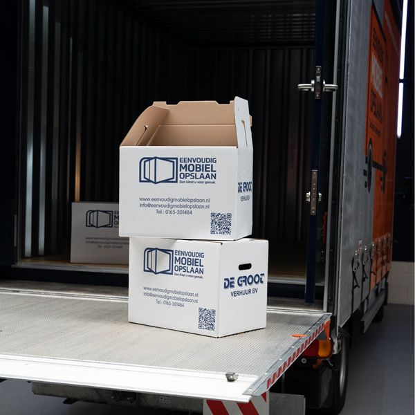 Stevige verhuisdozen met Eenvoudig Mobiel Opslaan logo op laadklep Twee verhuisdozen op laadklep bakwagen – verhuisdozen kopen bij Eenvoudig Mobiel Opslaan