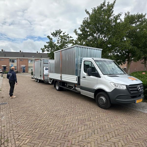 Bakwagen met twee opslagcontainers op aanhanger bij woningontruiming in woonwijk – Eenvoudig Mobiel Opslaan